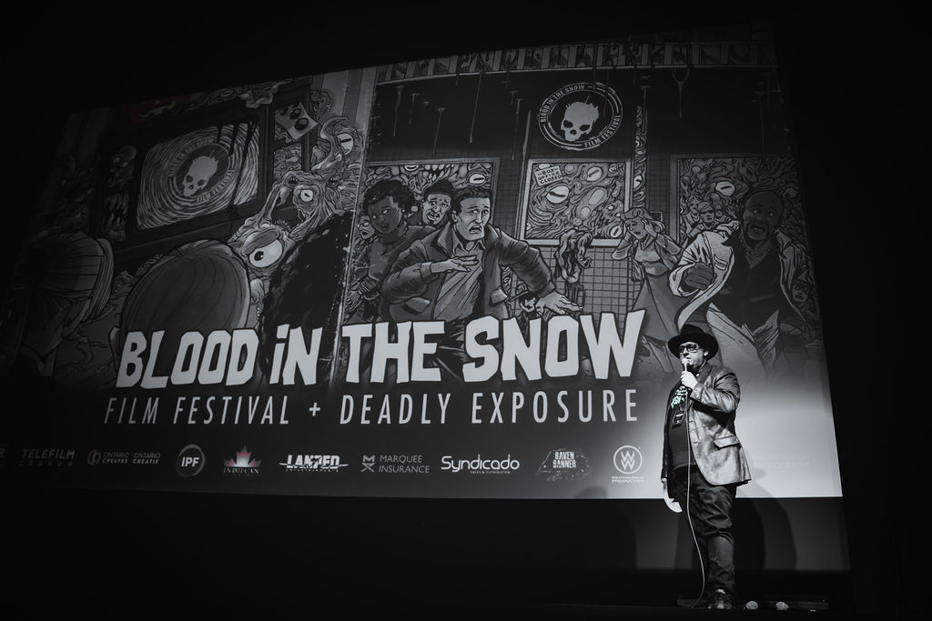 Photograph of Festival Director Kelly Michael Stewart on stage at the theatre announcing a screening